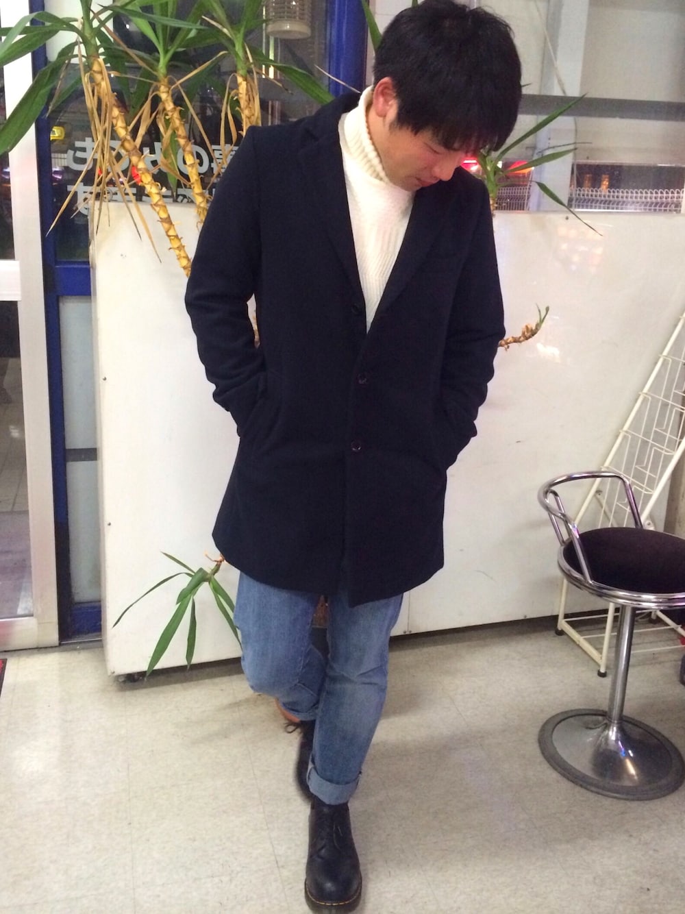 ブラック系のブーツ、ブルー系のチェスターコート、ホワイト系のニット/セーターを着用したメンズの冬コーディネートの1枚目の写真