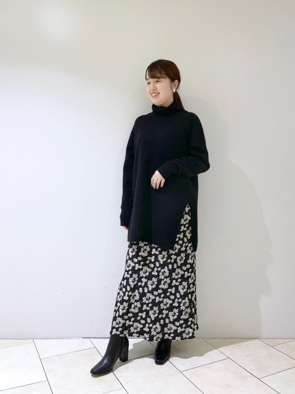 ブラック系のニット/セーター、ブラック系のスカート、ブラック系のブーツを着用したレディースの冬コーディネートの1枚目の写真