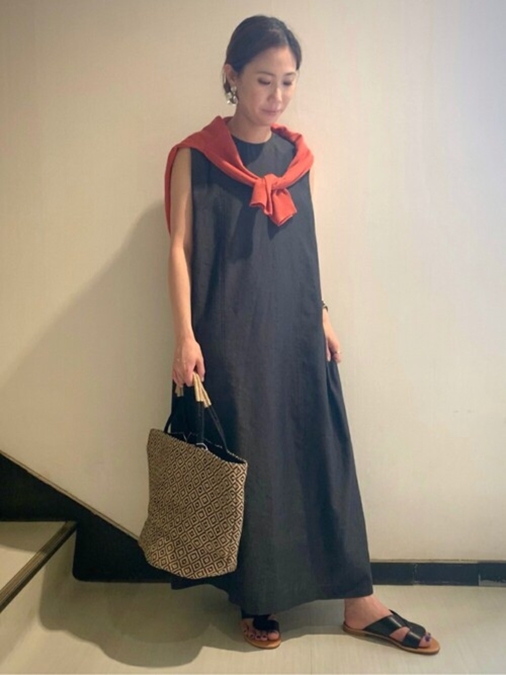 グレー系のワンピース、オレンジ系のカーディガン/ボレロ、ブラック系のサンダルを着用したレディースの夏コーディネートの1枚目の写真