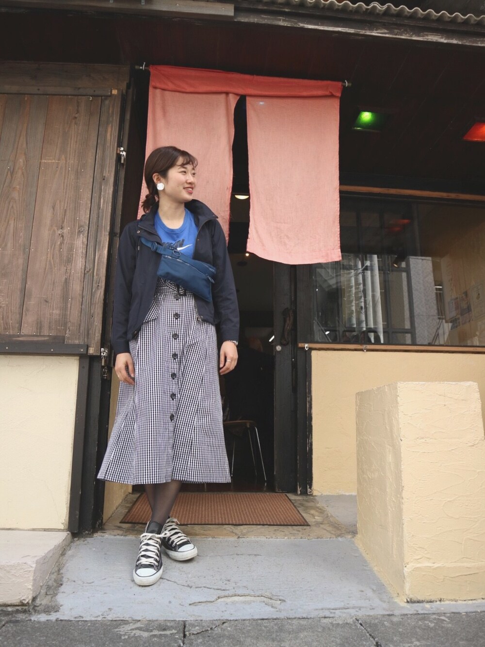 ブルー系のマウンテンパーカー、ブルー系のボディバッグ/ウエストポーチ、ブラック系のスカートを着用したレディースの春コーディネートの1枚目の写真