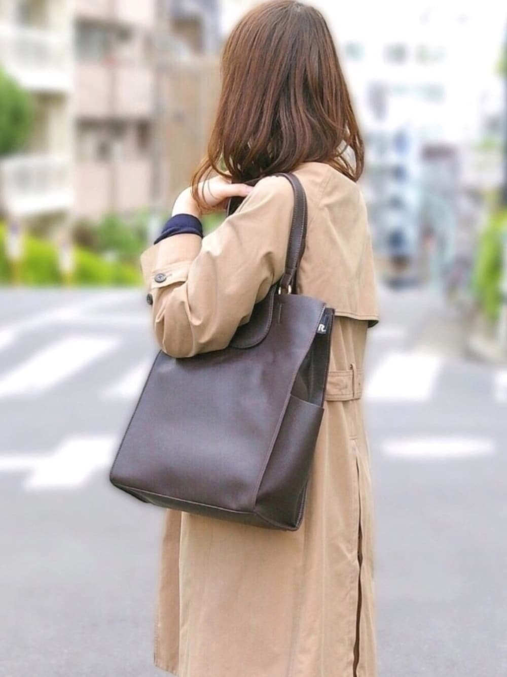 ブラウン系のビジネスバッグを着用したレディースの秋コーディネートの1枚目の写真