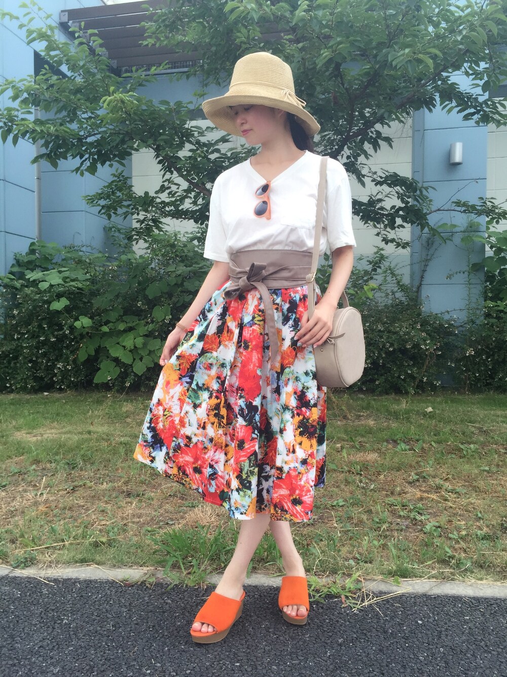 レッド系のスカート、ベージュ系のショルダーバッグ、オレンジ系のサンダルを着用したレディースの夏コーディネートの1枚目の写真