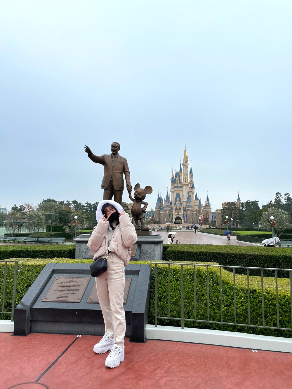 ホワイト系のデニムパンツ、ブラック系のショルダーバッグ、ベージュ系のダウンジャケット/コートを着用したレディースの冬コーディネートの1枚目の写真