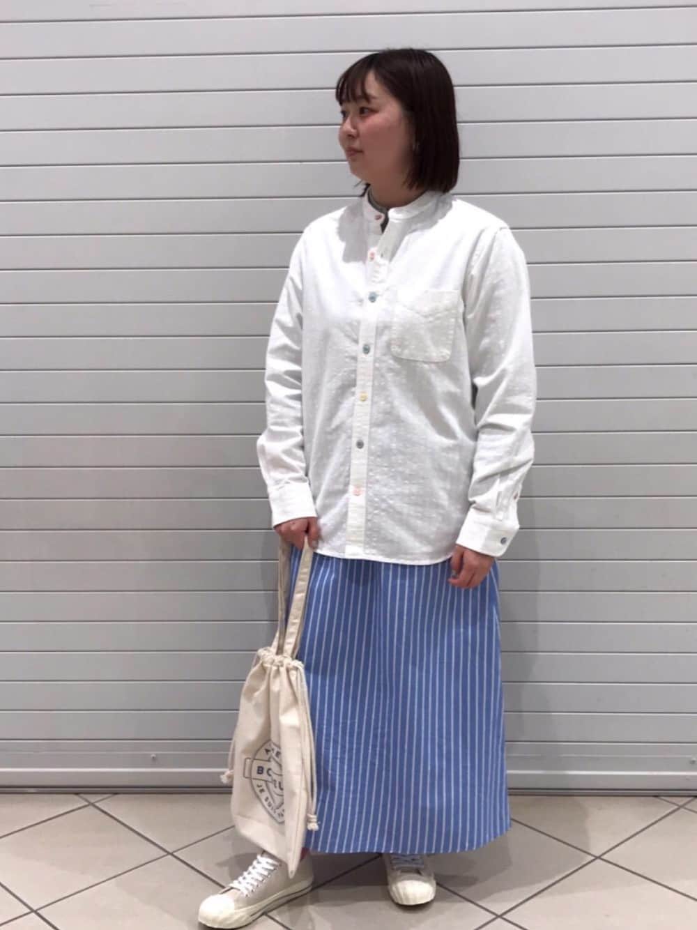 ベージュ系のスニーカー、グリーン系のTシャツ/カットソー、ブルー系のスカートを着用したレディースの春コーディネートの1枚目の写真