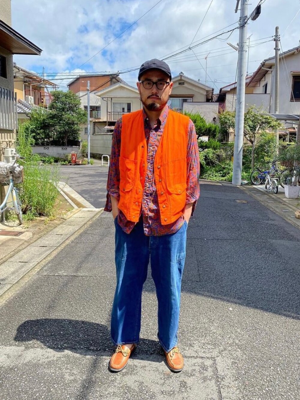 オレンジ系のベスト、レッド系のシャツ/ブラウス、ブルー系のデニムパンツを着用したメンズの冬コーディネートの1枚目の写真