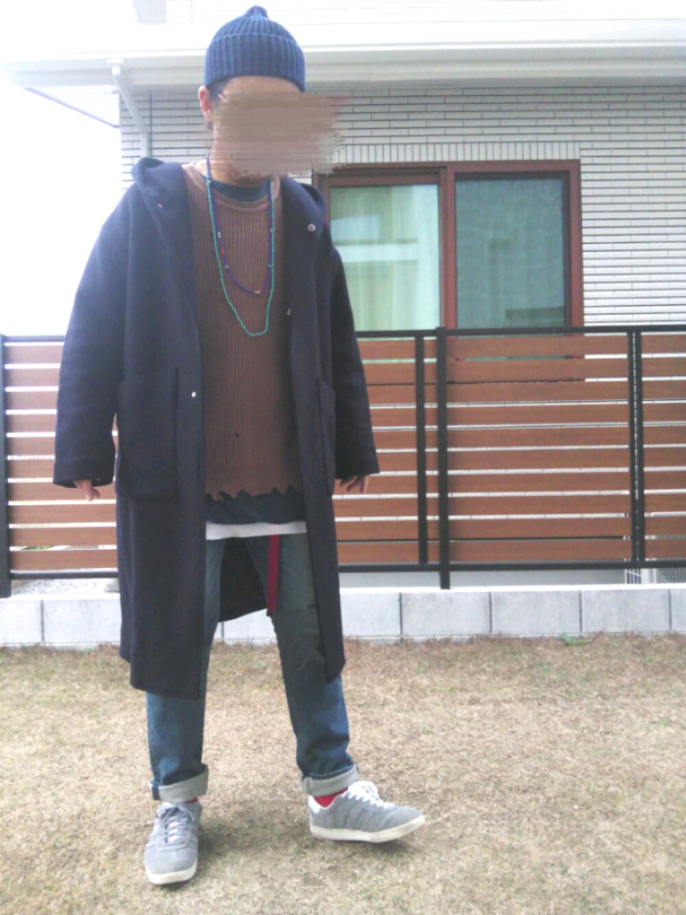 ブルー系のチェスターコート、グレー系のスニーカー、ブラウン系のニット/セーターを着用したメンズの冬コーディネートの1枚目の写真