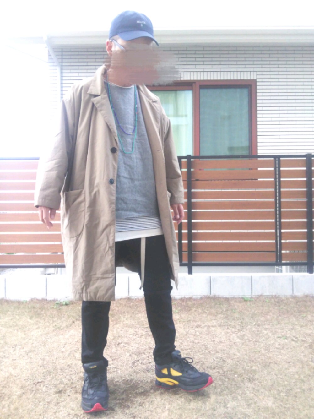 ベージュ系のステンカラーコート、ブラック系のデニムパンツ、グレー系のニット/セーターを着用したメンズの冬コーディネートの1枚目の写真