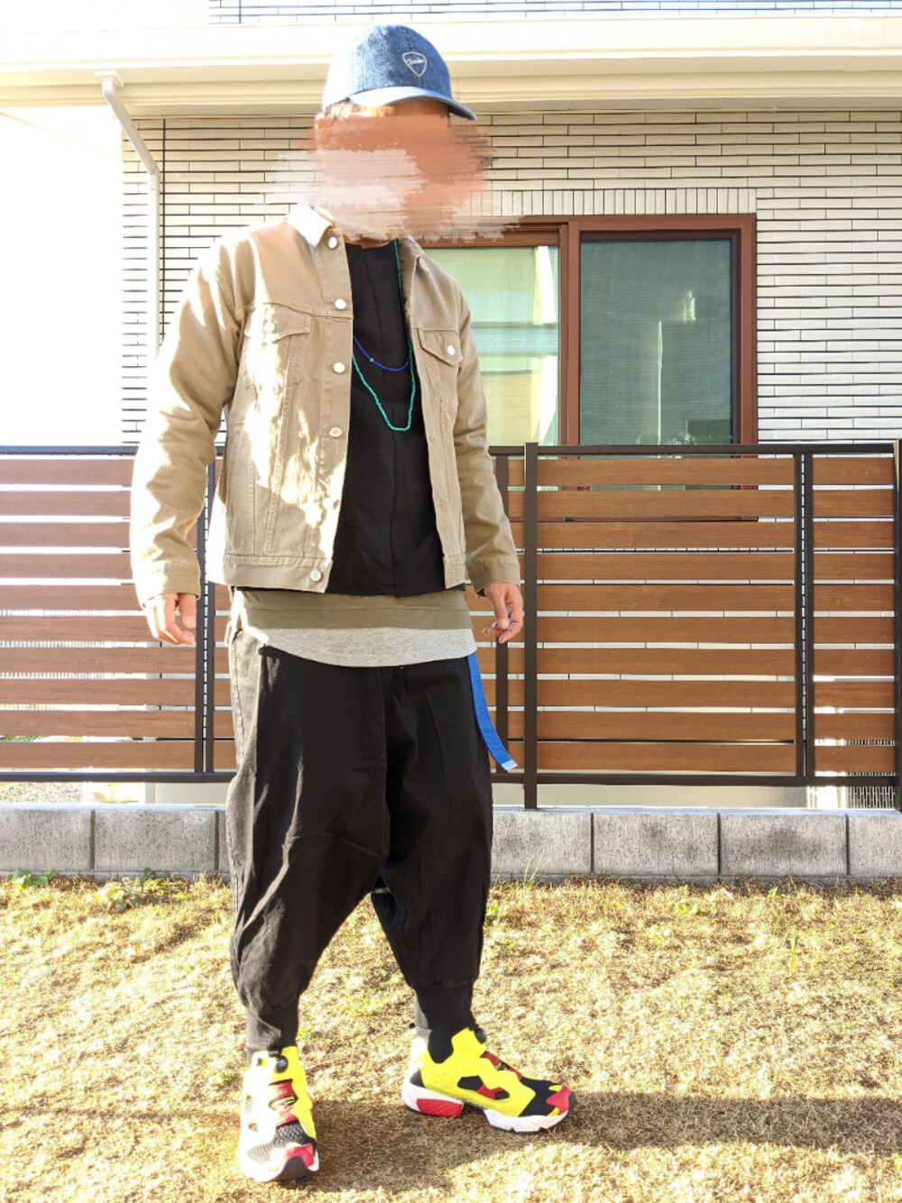 ベージュ系のデニムジャケット、ブラック系のスニーカー、グレー系のタンクトップを着用したメンズの春コーディネートの1枚目の写真