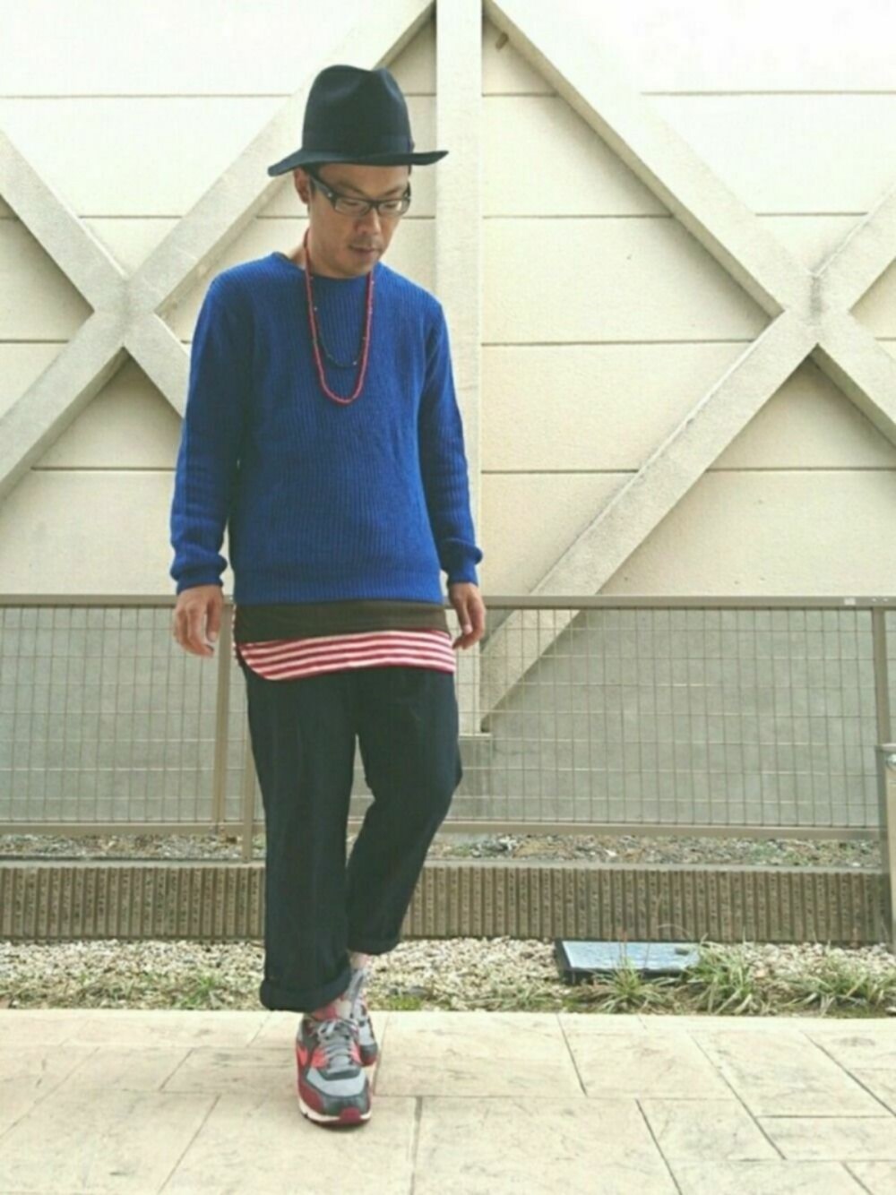 ピンク系のスニーカー、ブルー系のニット/セーター、レッド系のタンクトップを着用したメンズの秋コーディネートの1枚目の写真