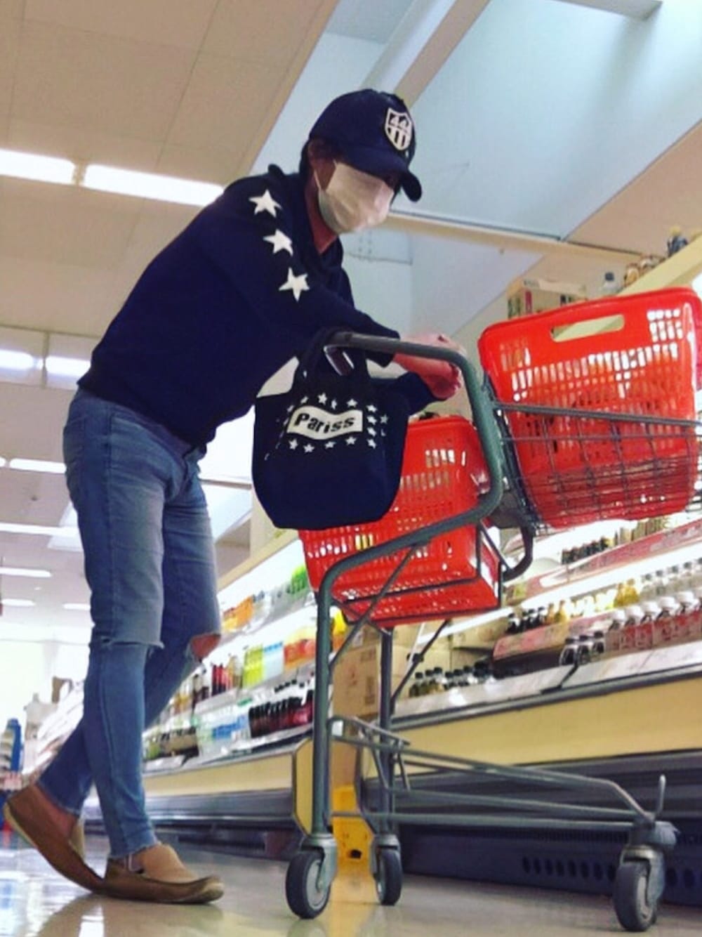 ブラック系のパーカー、ブラック系のトートバッグ、ブルー系のデニムパンツを着用したメンズの秋コーディネートの1枚目の写真