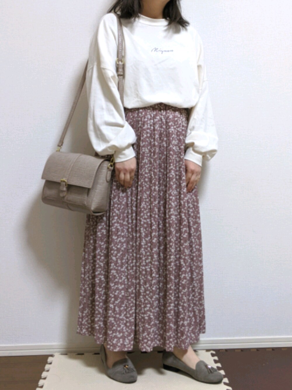 グレー系のパンプス、ピンク系のスカート、ホワイト系のTシャツ/カットソーを着用したレディースの冬コーディネートの1枚目の写真