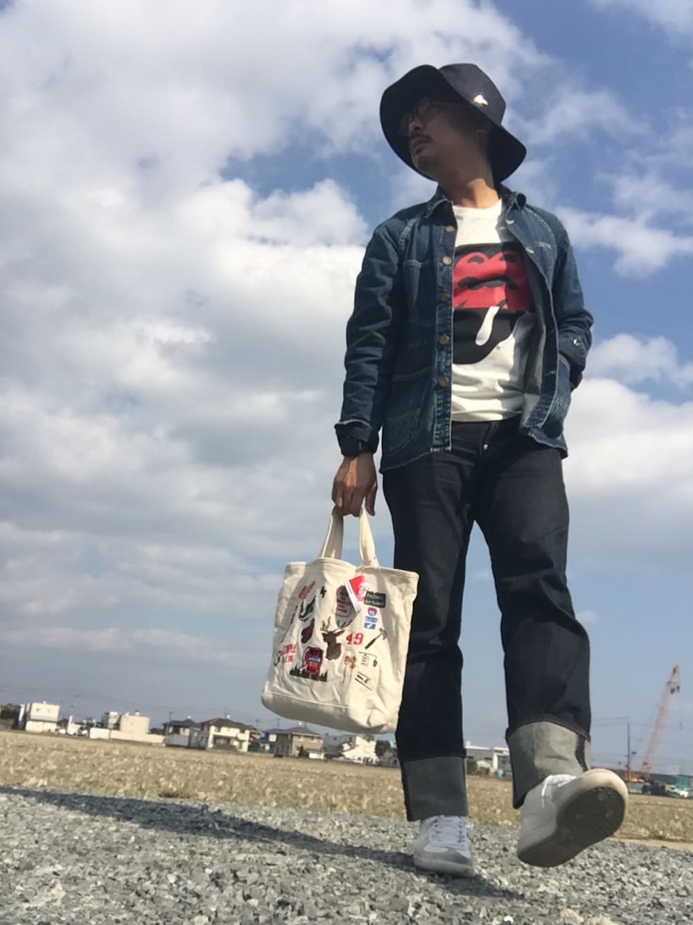 ブルー系のカバーオール、レッド系のTシャツ/カットソー、ブルー系のデニムパンツを着用したメンズの春コーディネートの1枚目の写真