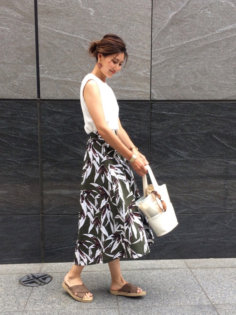 グリーン系のスカート、グリーン系のサンダル、ホワイト系のトートバッグを着用したレディースの夏コーディネートの1枚目の写真