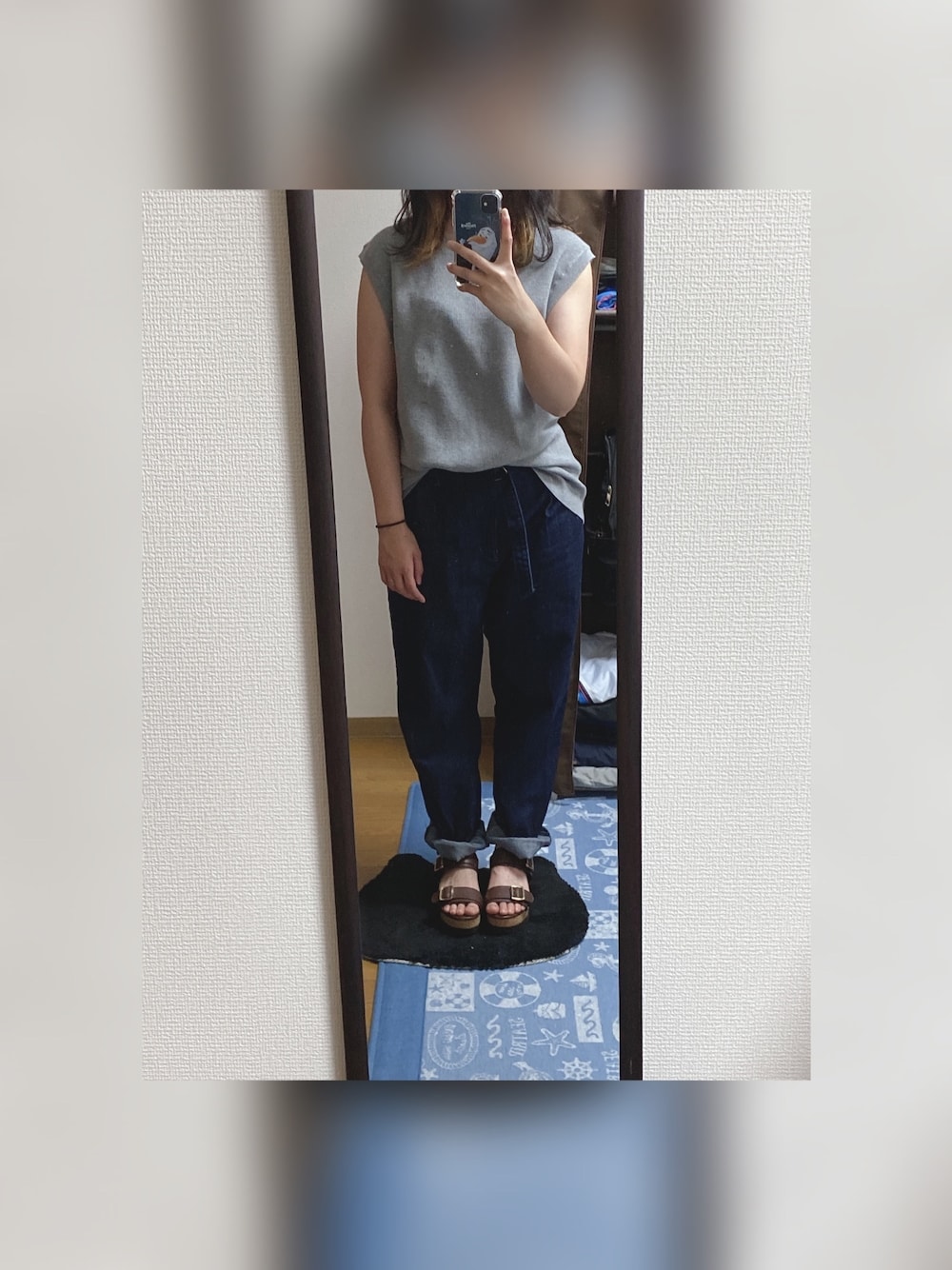 グレー系のニット/セーター、ブルー系のデニムパンツ、ブラウン系のサンダルを着用したレディースの春コーディネートの1枚目の写真
