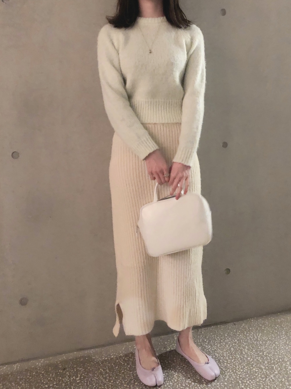 グリーン系のニット/セーター、ホワイト系のハンドバッグ、パープル系のバレエシューズを着用したレディースの冬コーディネートの1枚目の写真