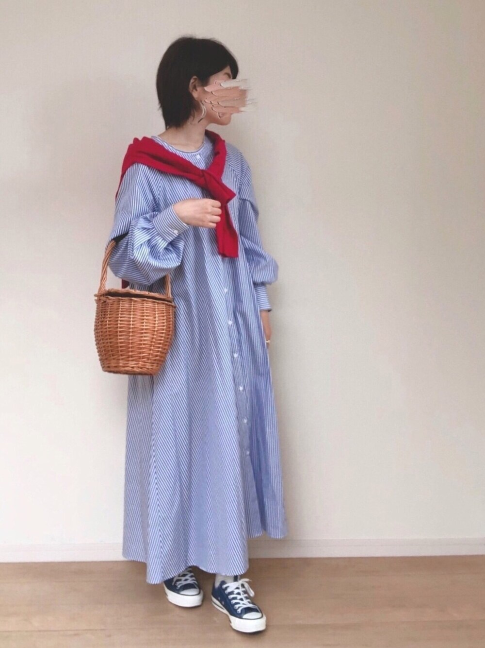 ブルー系のシャツワンピース、ベージュ系のかごバッグ、ブルー系のスニーカーを着用したレディースの春コーディネートの1枚目の写真