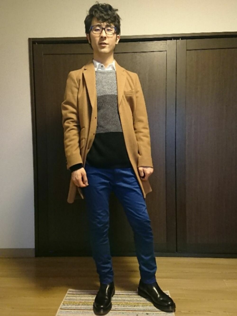 ブラック系のブーツ、ブルー系のチノパンツ、ブラック系のニット/セーターを着用したメンズの春コーディネートの1枚目の写真