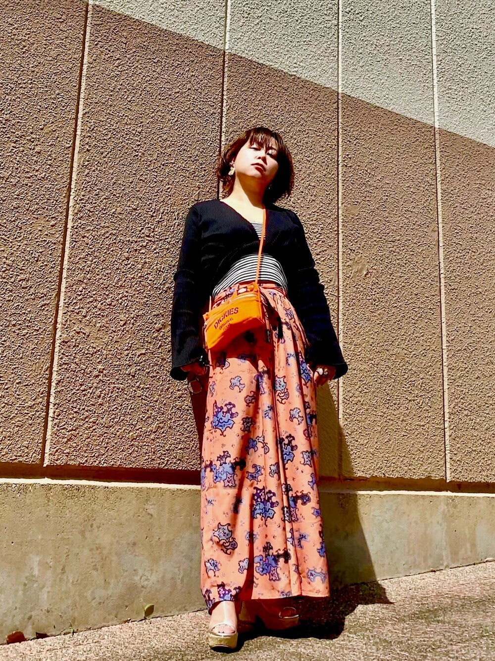 ブラック系のTシャツ/カットソー、オレンジ系のその他パンツ、オレンジ系のショルダーバッグを着用したレディースの春コーディネートの1枚目の写真