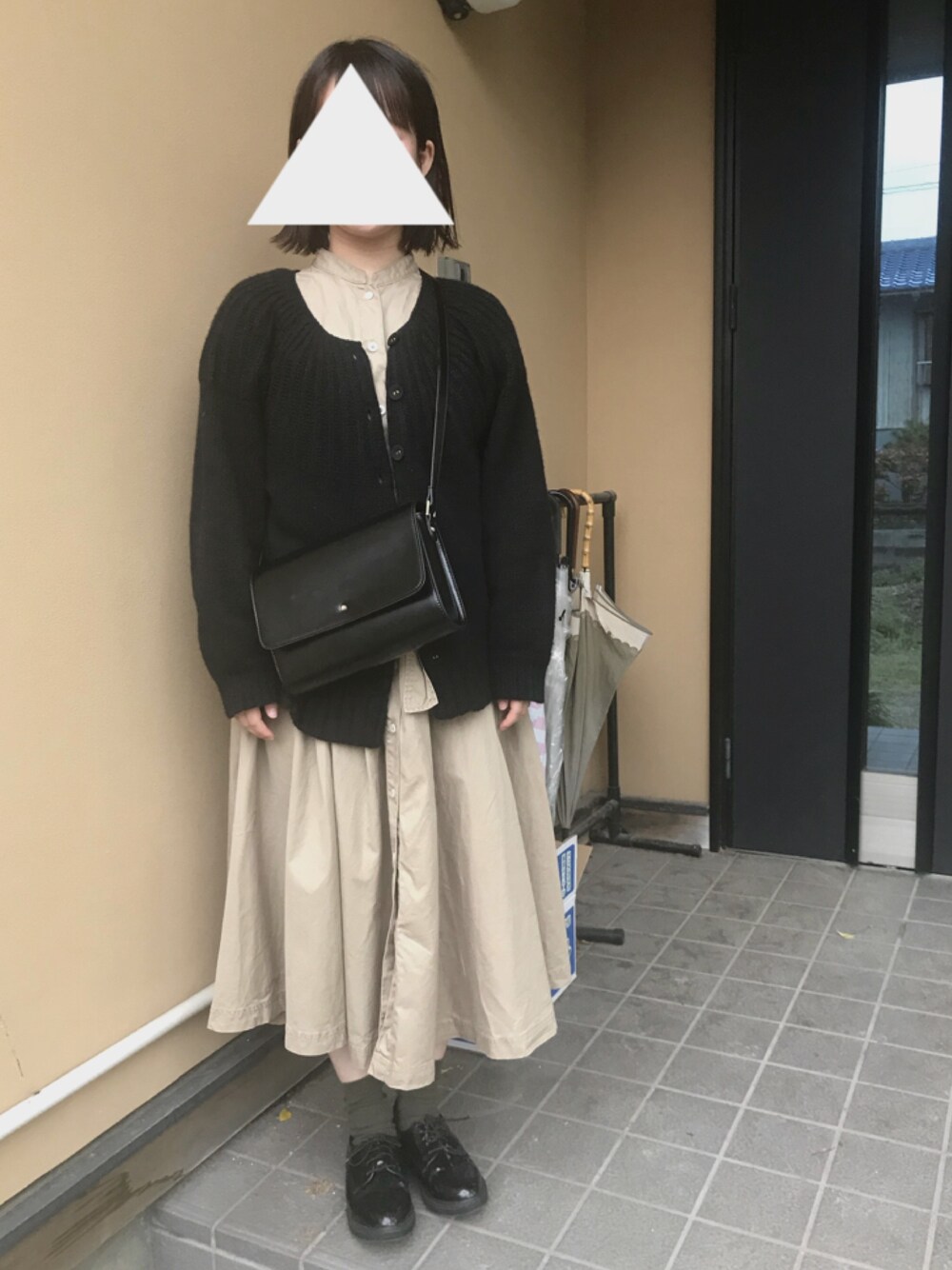 ブラック系のトップス、ベージュ系のシャツワンピース、ブラック系のショルダーバッグを着用したレディースの春コーディネートの1枚目の写真