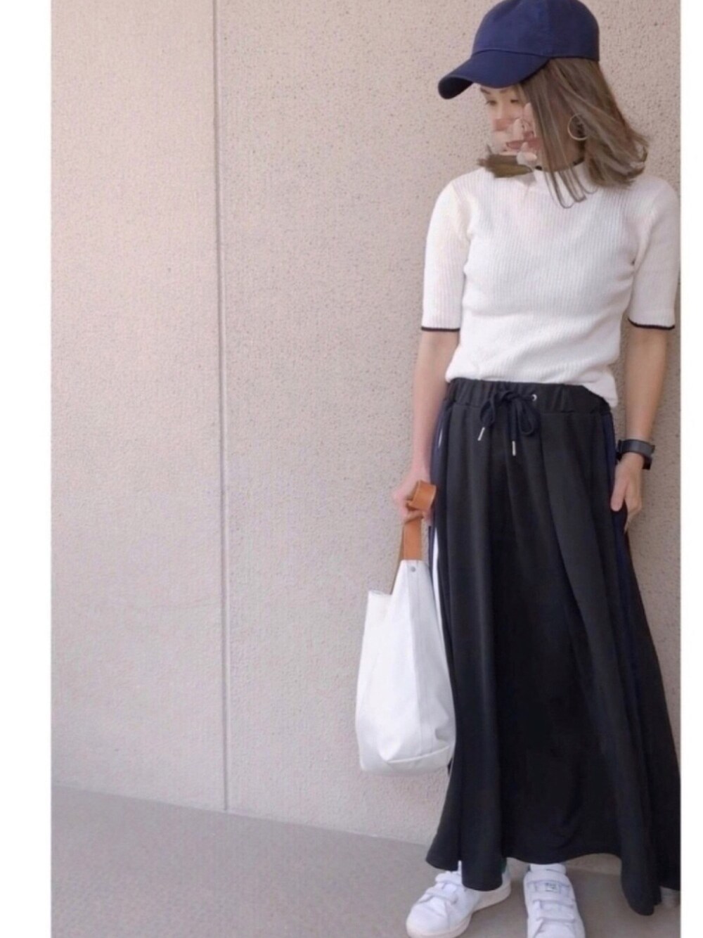 ホワイト系のニット/セーター、ブラック系のスカート、ホワイト系のバッグを着用したレディースの春コーディネートの1枚目の写真