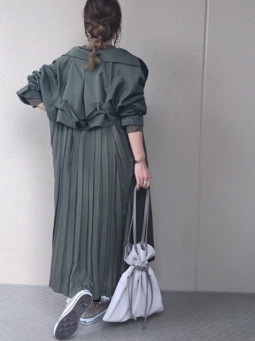 グリーン系のトレンチコート、ベージュ系のトートバッグ、ベージュ系のスニーカーを着用したレディースの秋コーディネートの1枚目の写真