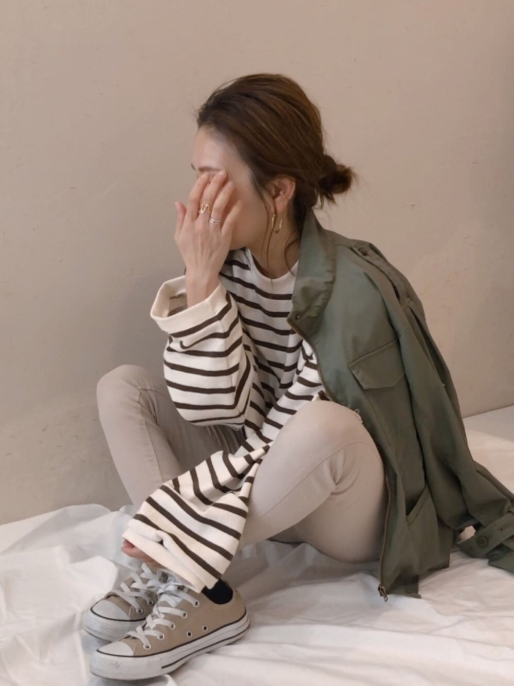 グリーン系のマウンテンパーカー、ベージュ系のTシャツ/カットソー、ベージュ系のパンツを着用したレディースの冬コーディネートの1枚目の写真