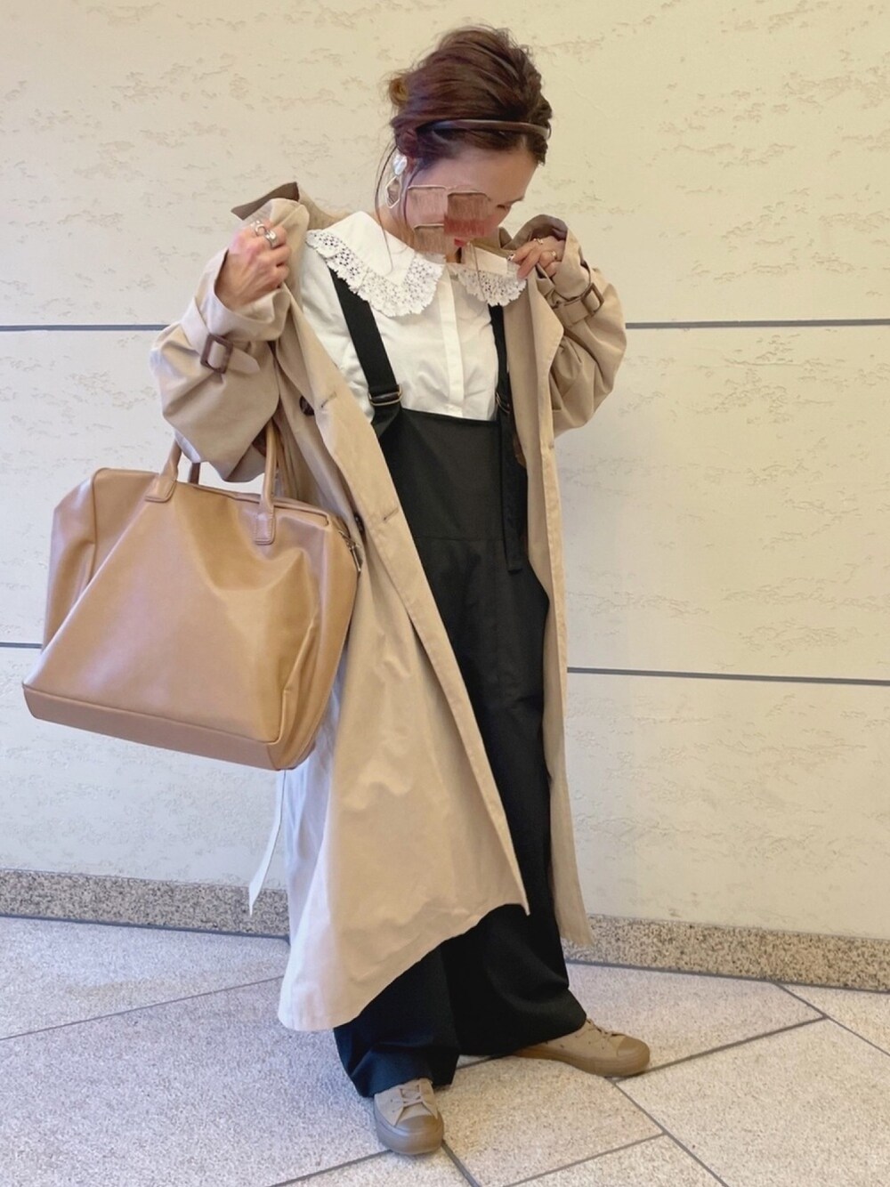 ベージュ系のトレンチコート、ホワイト系のシャツ/ブラウス、ブラック系のつなぎ/オールインワンを着用したレディースの冬コーディネートの1枚目の写真