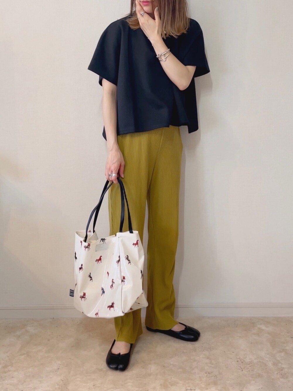 ブラック系のTシャツ/カットソー、イエロー系のその他パンツ、ベージュ系のトートバッグを着用したレディースの春コーディネートの1枚目の写真