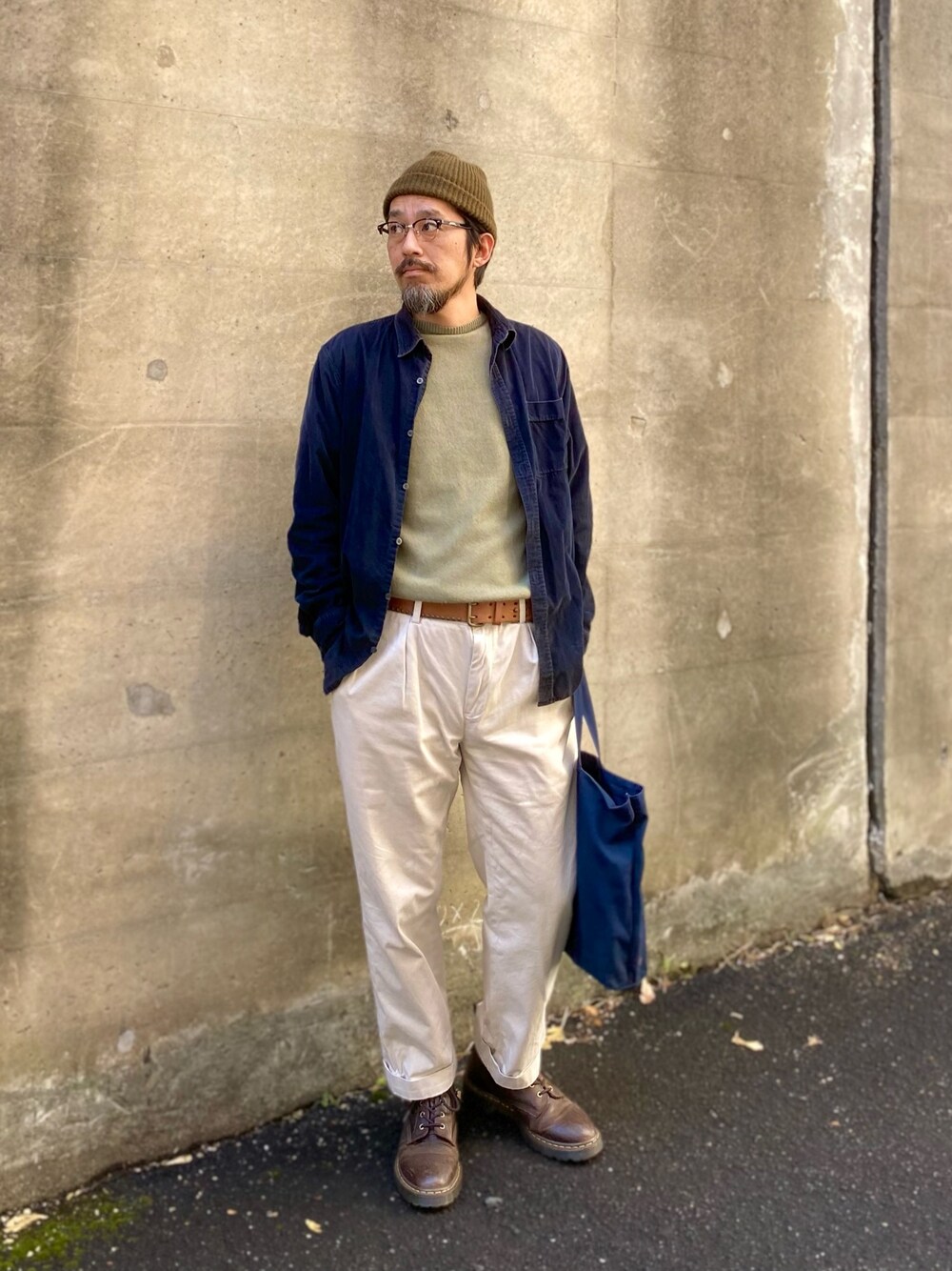 グリーン系のニット/セーター、ブルー系のシャツ/ブラウス、ホワイト系のチノパンツを着用したメンズの冬コーディネートの1枚目の写真