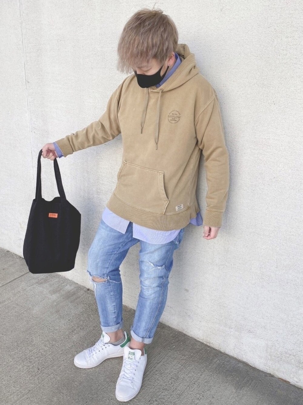 ブラック系のトートバッグ、ブルー系のデニムパンツ、ベージュ系のパーカーを着用したメンズの春コーディネートの1枚目の写真