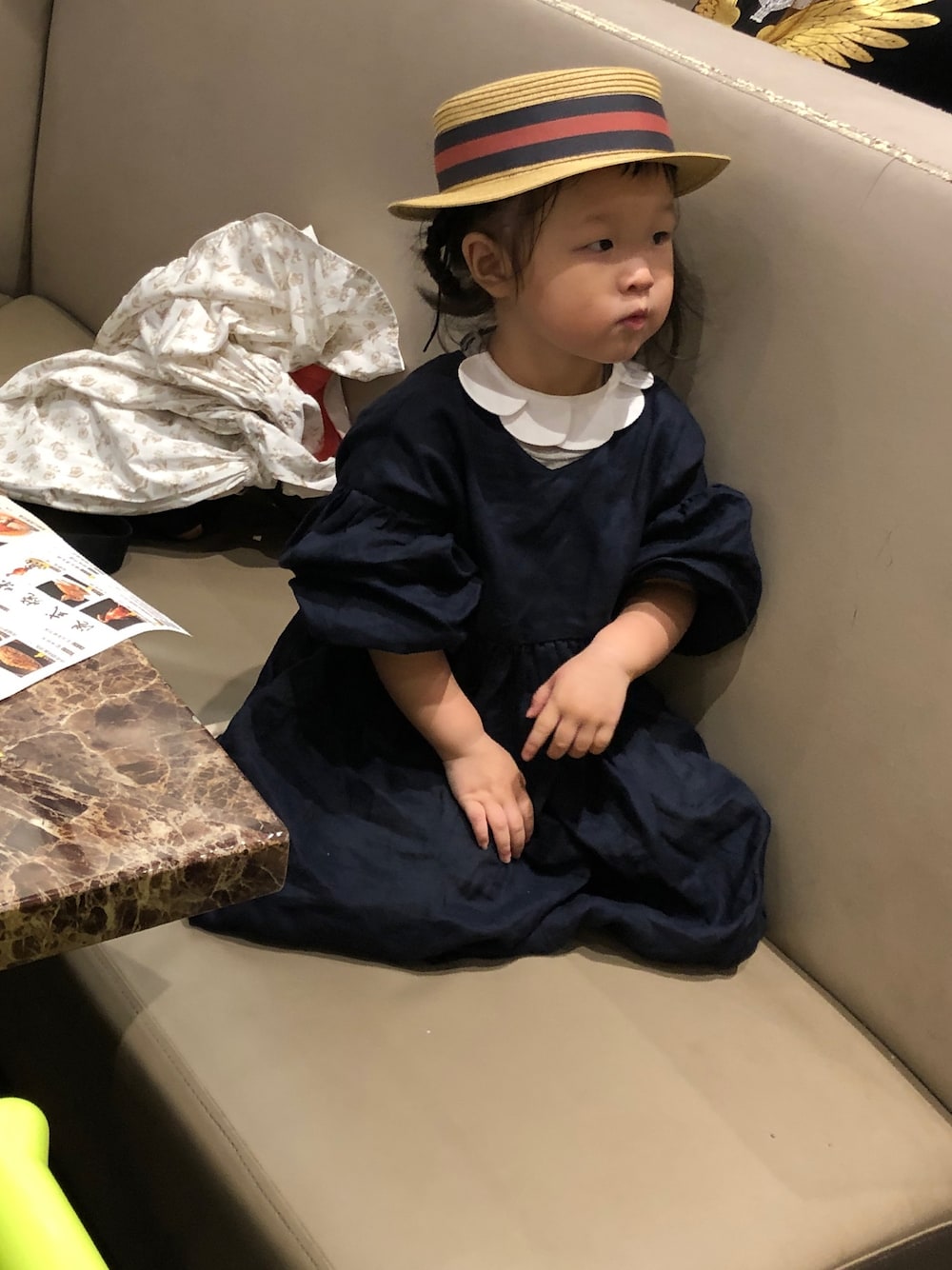 ブラック系のロンパース、ベージュ系のキャップを着用したキッズの秋コーディネートの1枚目の写真