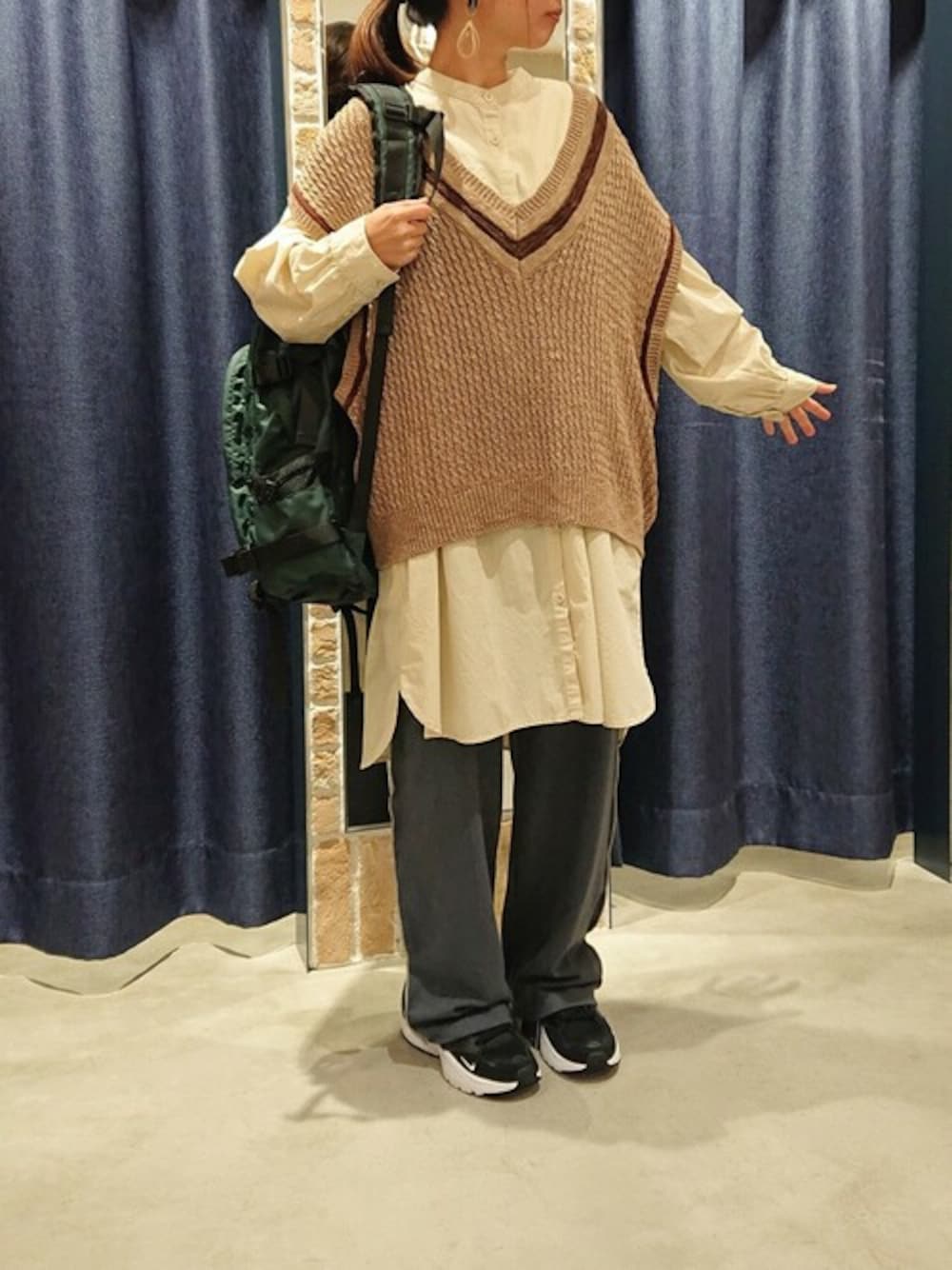 ブラック系のその他パンツ、ベージュ系のニット/セーター、グリーン系のバックパック/リュックを着用したレディースの秋コーディネートの1枚目の写真