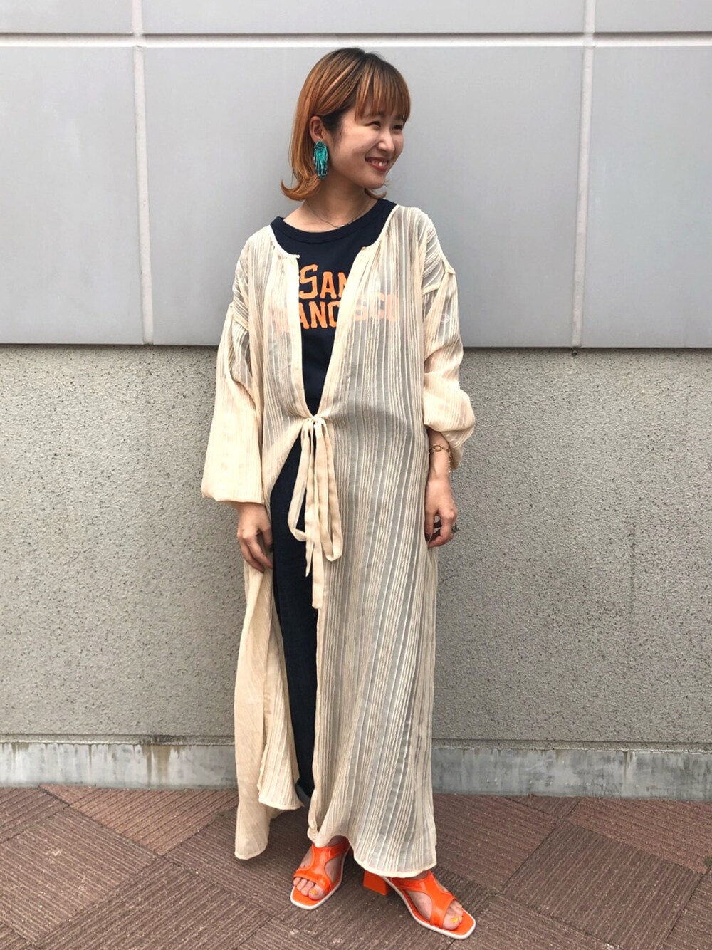 ベージュ系のワンピース、ブルー系のTシャツ/カットソー、ブルー系のデニムパンツを着用したレディースの夏コーディネートの1枚目の写真