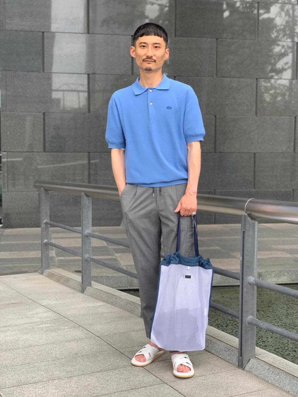 ブルー系のポロシャツ、ホワイト系のサンダル、グレー系のその他パンツを着用したメンズの夏コーディネートの1枚目の写真
