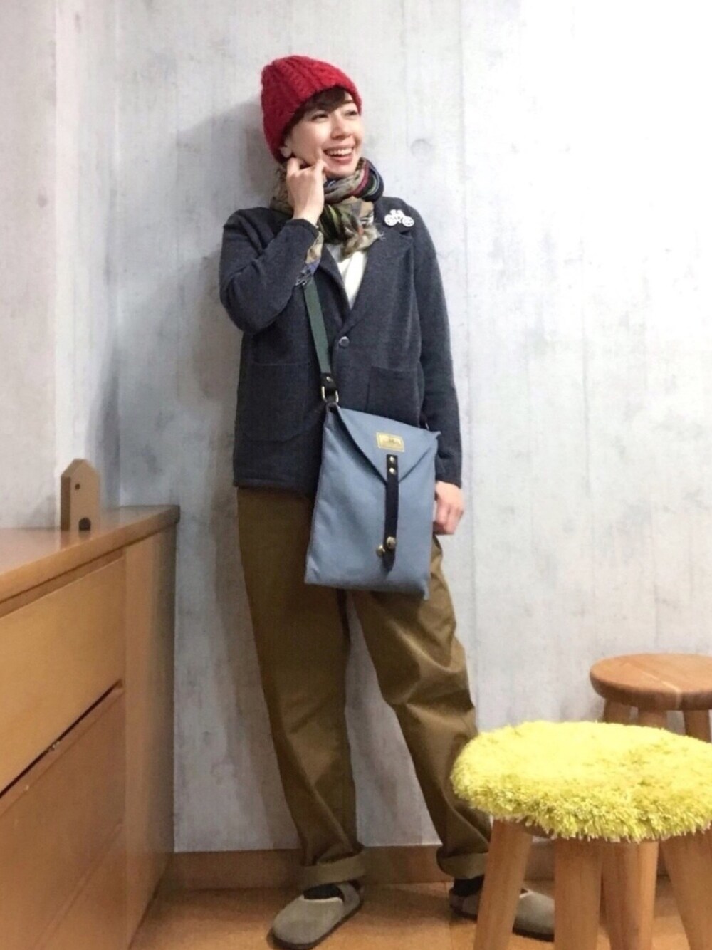 グリーン系のショルダーバッグ、ブラウン系のチノパンツ、ベージュ系のサンダルを着用したレディースの春コーディネートの1枚目の写真