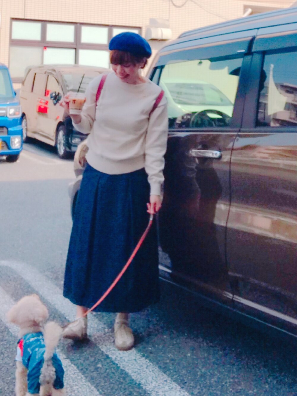 ブルー系のデニムスカート、ホワイト系のニット/セーター、ホワイト系のスニーカーを着用したレディースの春コーディネートの1枚目の写真