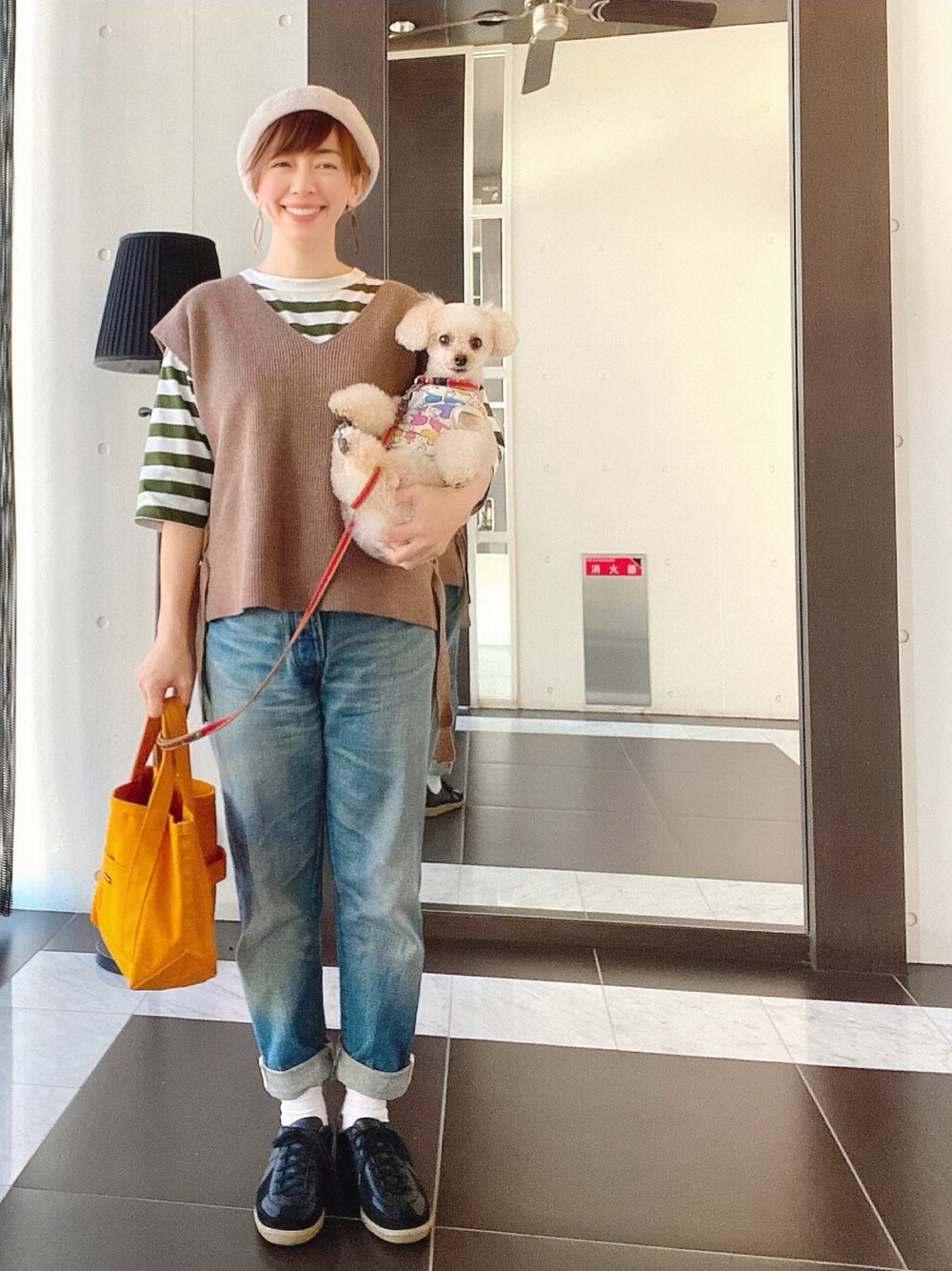 グリーン系のTシャツ/カットソー、ブラウン系のベスト、ブルー系のデニムパンツを着用したレディースの秋コーディネートの1枚目の写真