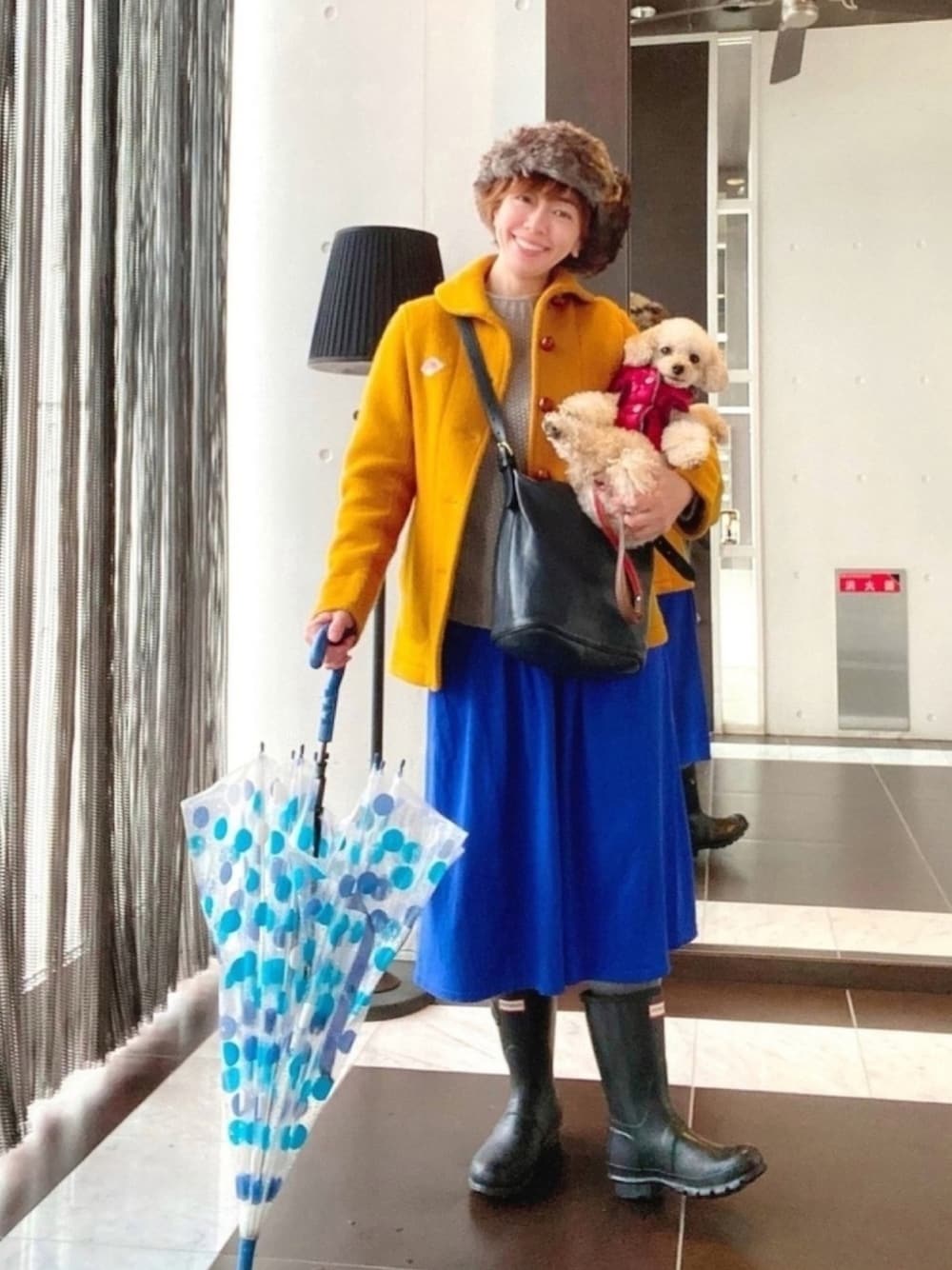 イエロー系のジャケット/アウター、グレー系のニット/セーター、ブルー系のスカートを着用したレディースの秋コーディネートの1枚目の写真