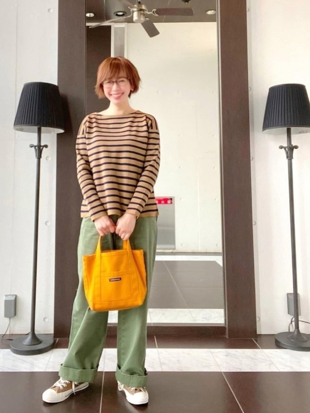 ブラウン系のTシャツ/カットソー、グリーン系のその他パンツ、イエロー系のトートバッグを着用したレディースの冬コーディネートの1枚目の写真