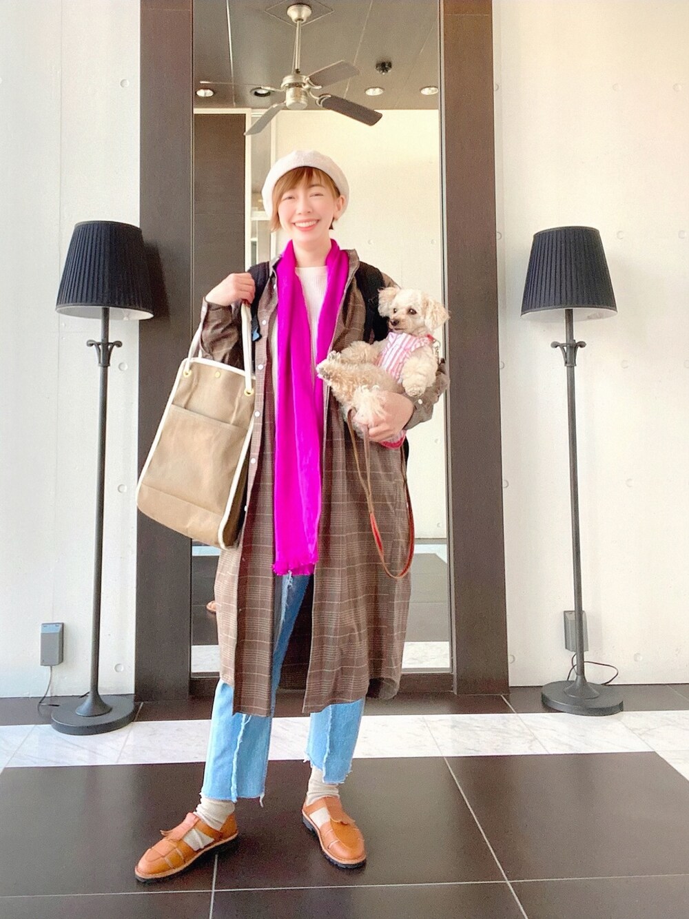 ブラウン系のシャツワンピース、ホワイト系のTシャツ/カットソー、ブルー系のデニムパンツを着用したレディースの春コーディネートの1枚目の写真