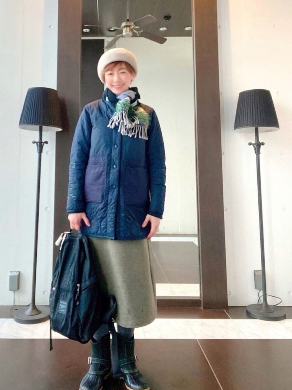 ブルー系のダウンジャケット/コート、ブルー系のニット/セーター、グリーン系のスカートを着用したレディースの春コーディネートの1枚目の写真