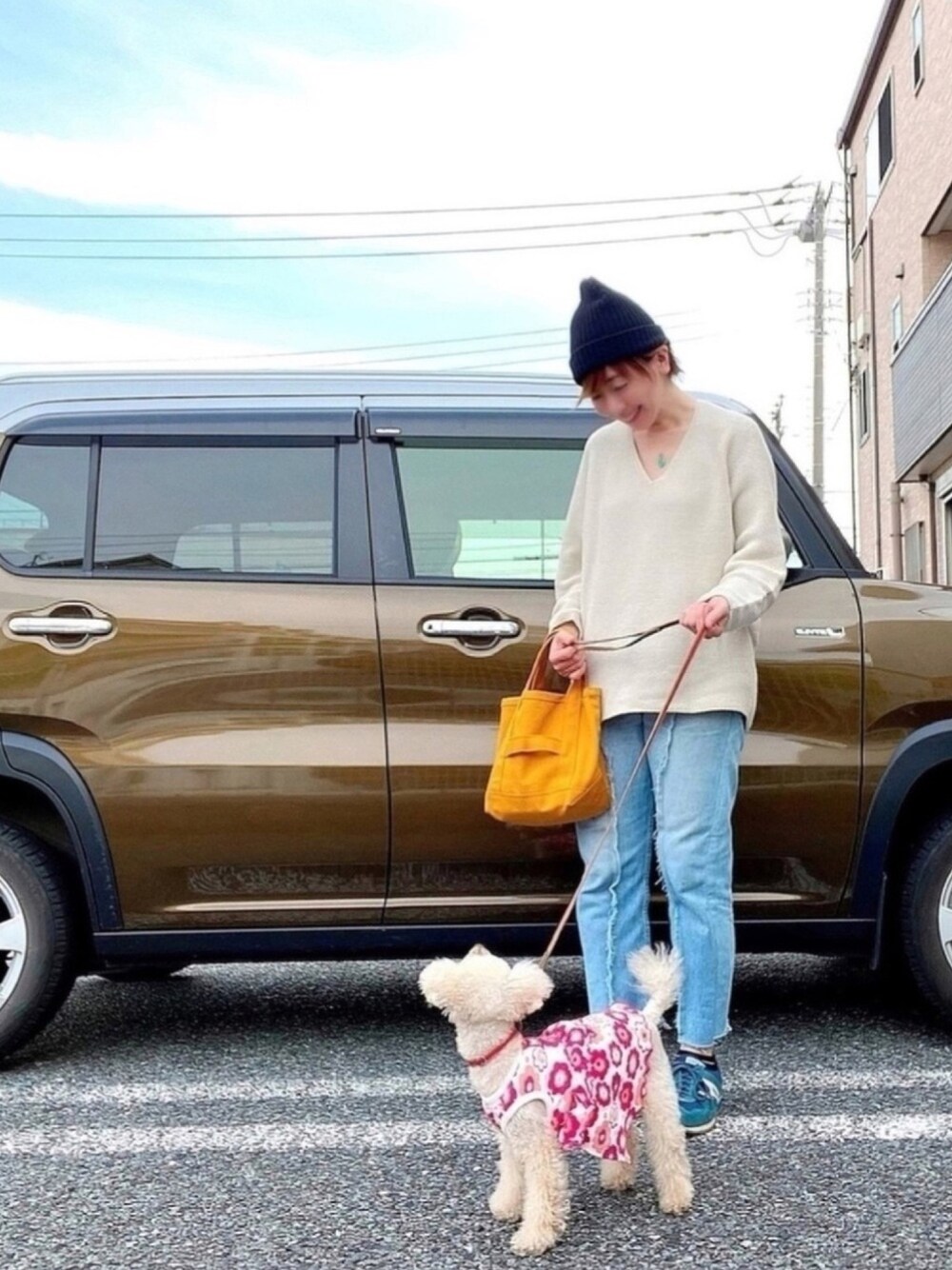 ベージュ系のニット/セーター、ブルー系のデニムパンツ、イエロー系のトートバッグを着用したレディースの春コーディネートの1枚目の写真