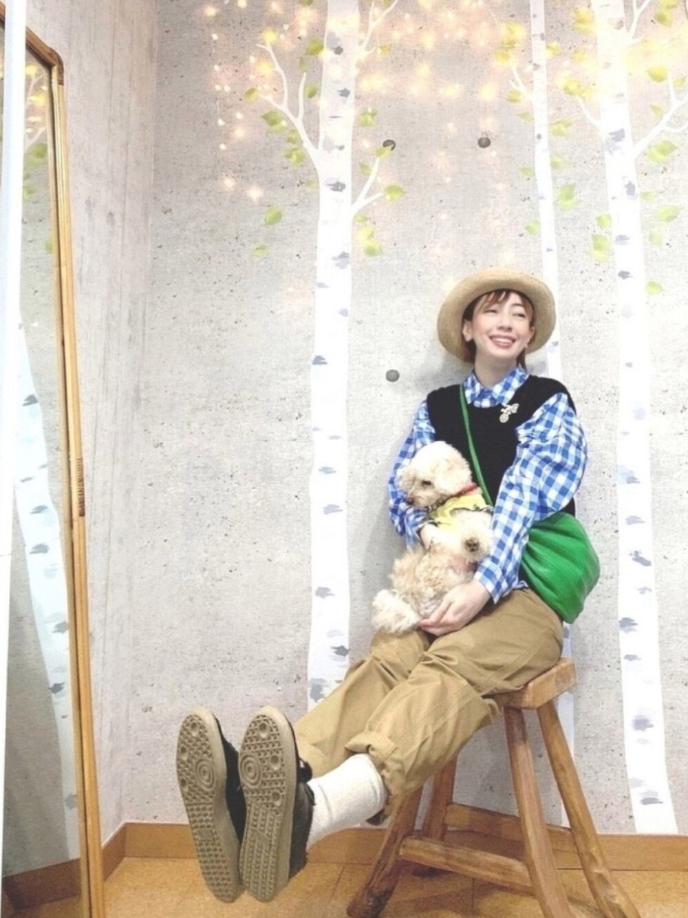 ブラック系のベスト、ベージュ系のチノパンツ、イエロー系のペットウェアを着用したレディースの春コーディネートの1枚目の写真