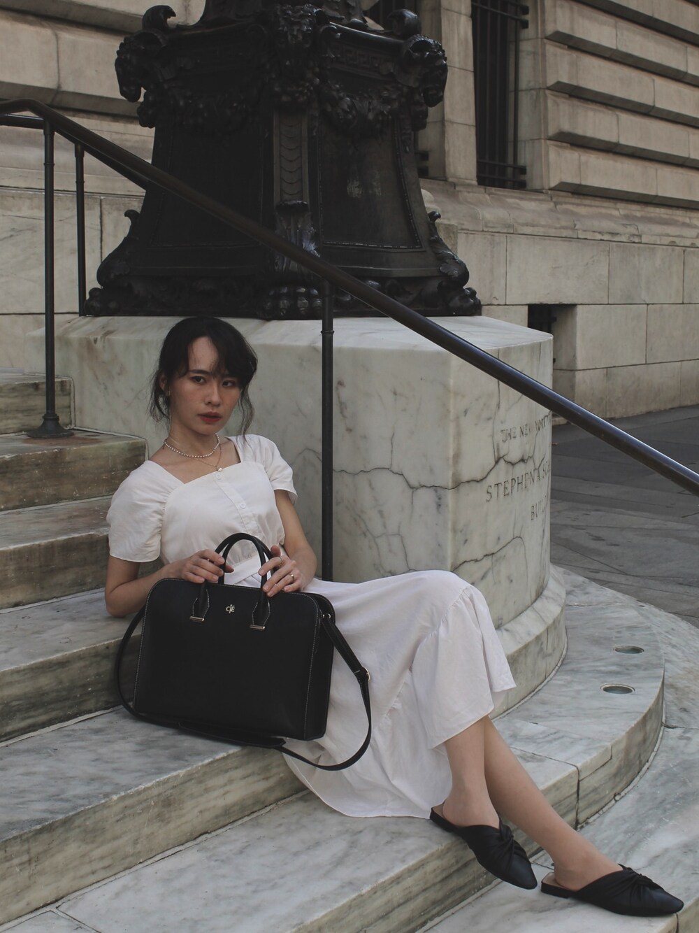 ブラック系のメッセンジャーバッグ、ホワイト系のワンピース、ホワイト系のネックレスを着用したレディースの夏コーディネートの1枚目の写真