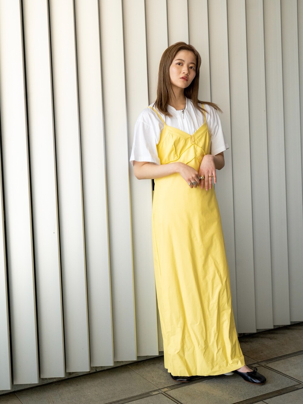 イエロー系のワンピース、ホワイト系のTシャツ/カットソー、ブラック系のバレエシューズを着用したレディースの冬コーディネートの1枚目の写真