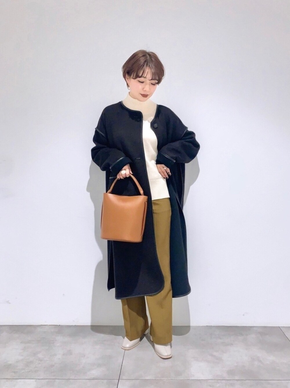 ホワイト系のニット/セーター、ブラック系のノーカラージャケット、ブラウン系のショルダーバッグを着用したレディースの冬コーディネートの1枚目の写真