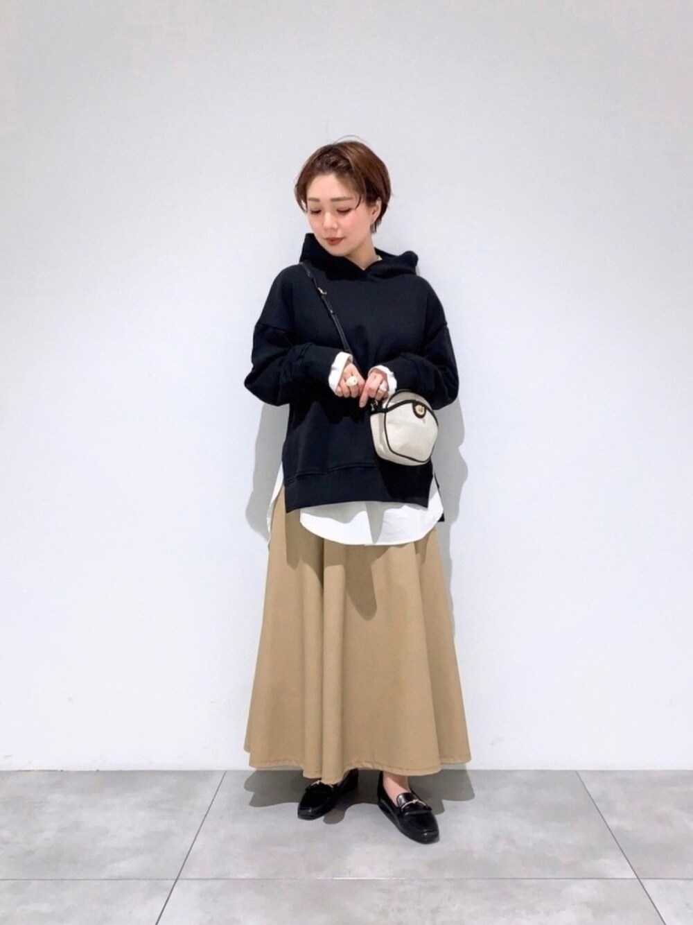 ブラック系のパーカー、ホワイト系のシャツ/ブラウス、ブラック系のローファーを着用したレディースの冬コーディネートの1枚目の写真