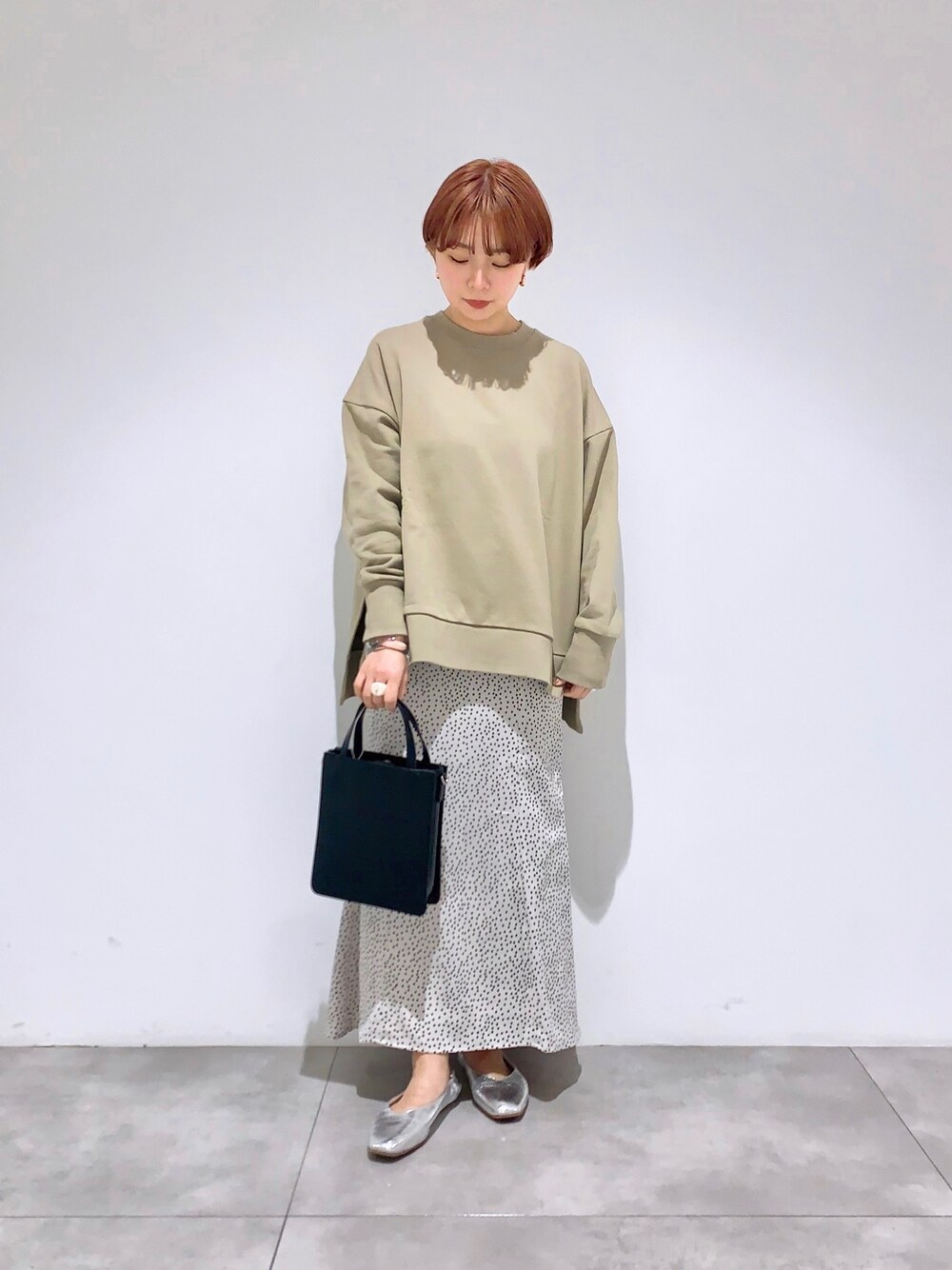 グリーン系のスウェット、ベージュ系のスカート、シルバー系のその他シューズを着用したレディースの春コーディネートの1枚目の写真