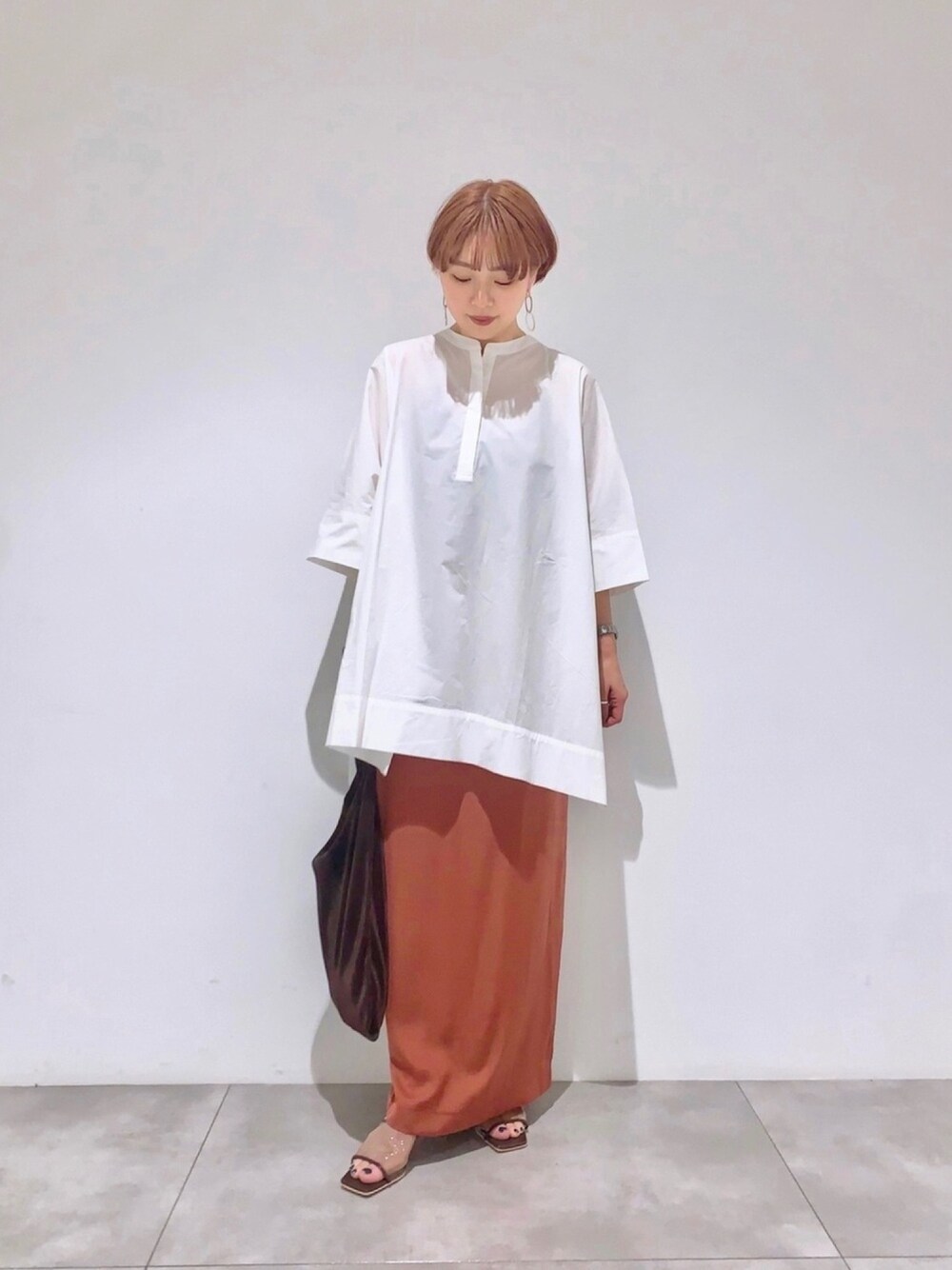 ブラック系のTシャツ/カットソー、レッド系のスカート、ブラウン系のサンダルを着用したレディースの春コーディネートの1枚目の写真