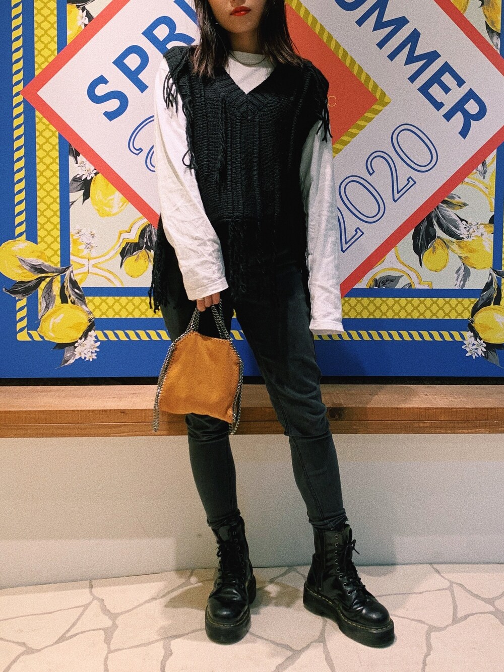 ブラック系のベスト、ブラウン系のバッグ、ホワイト系のTシャツ/カットソーを着用したレディースの秋コーディネートの1枚目の写真